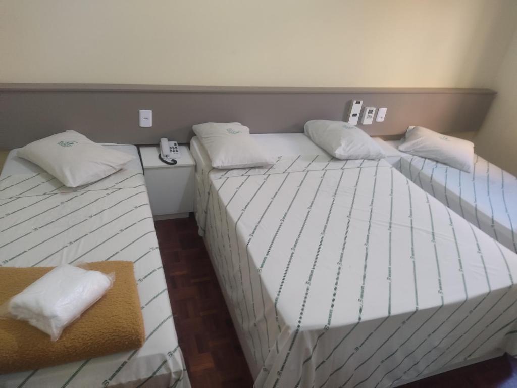 2 camas en una habitación con sábanas y almohadas blancas en Blanco Palace Hotel, en São José dos Campos