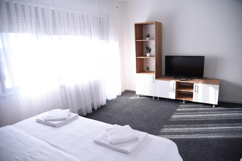 1 dormitorio con 1 cama, TV y cortinas en Vb apartmani en Prijedor