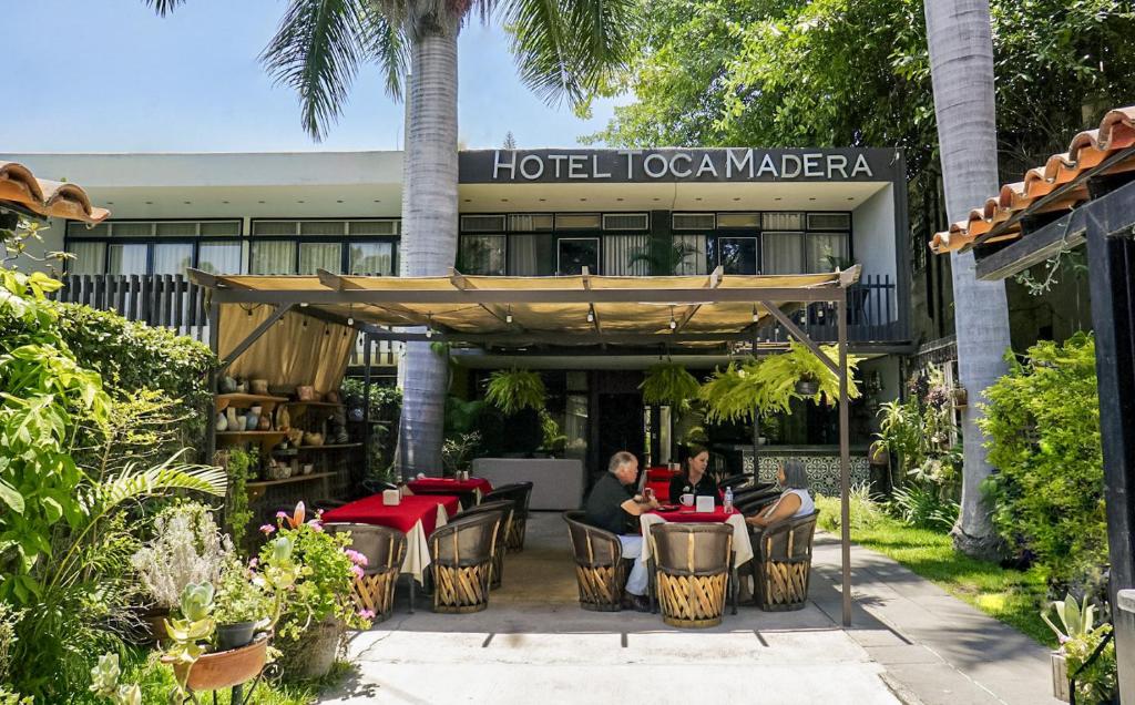 deux personnes assises à des tables devant un hôtel dans l'établissement Toca Madera, à Chapala