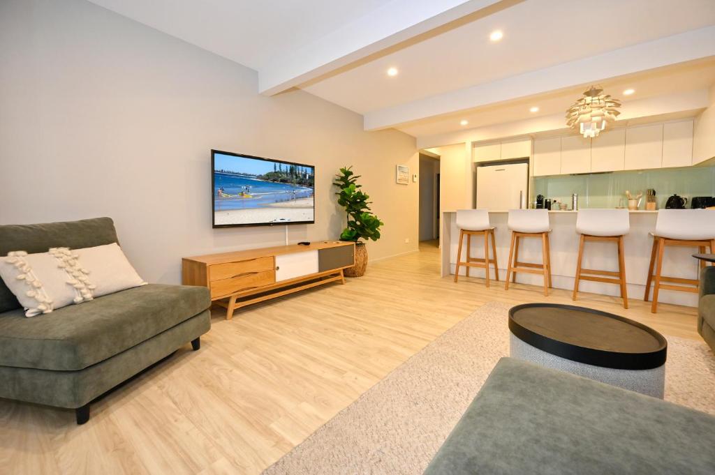 a living room with a couch and a tv and a kitchen at Stylish 2 b/r apartment - 4 guests, garage ZC5 in Alexandra Headland