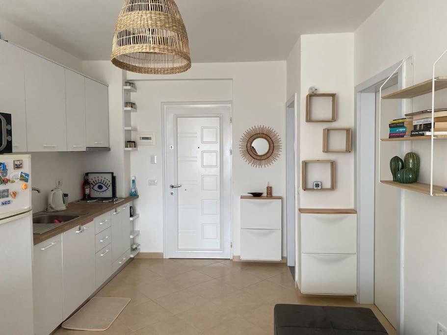 cocina con armarios blancos y puerta blanca en The Flip-Flop Apartment en Shëngjin