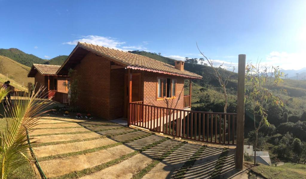 a small house with a balcony next to a mountain at Recanto João de barro in Visconde De Maua