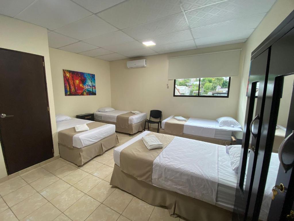 a room with four beds and a window at Hotel La Capilla - Suites & Apartments San Benito in San Salvador