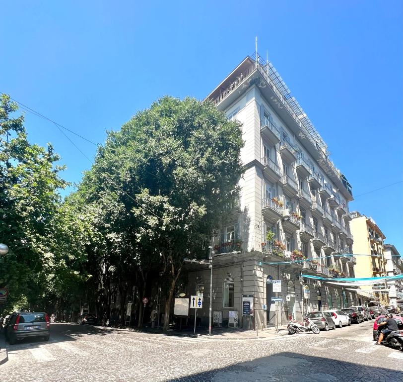 un grande edificio bianco con un albero di fronte di MILUAR Luxury B&B - Vanvitelli a Napoli