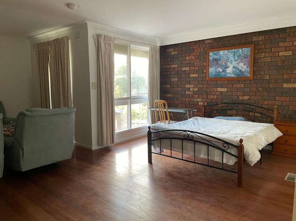 a bedroom with a bed and a brick wall at D High quality large bed rooms near commercial areas, universities, and rail transit in villas in Melbourne