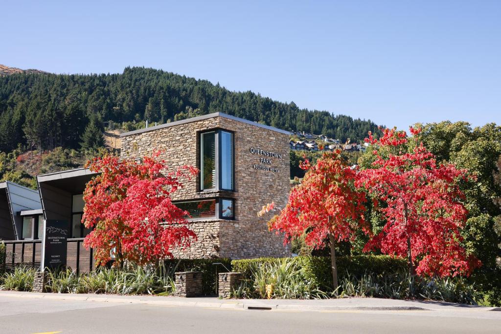 皇后鎮的住宿－皇后鎮公園精品酒店，前面有红树的砖房