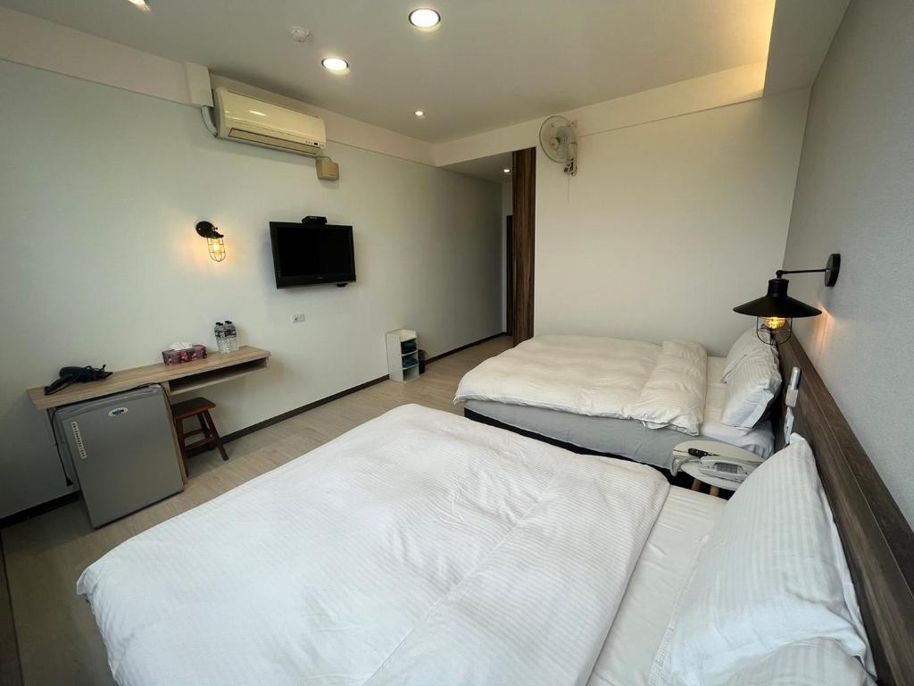 a room with two beds and a desk and a tv at Dongshan River Resort Farm in Wujie
