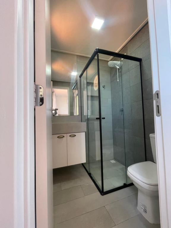 a bathroom with a glass shower and a toilet at Apartamento Praia de Carapibus in Conde