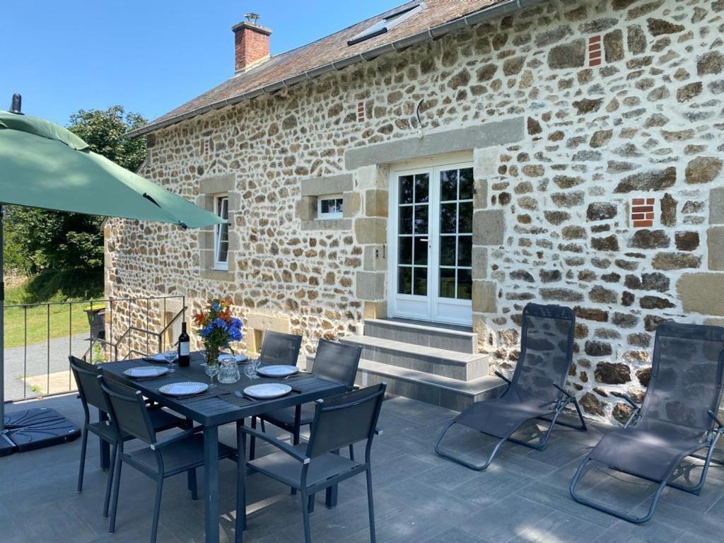 a patio with a table and chairs in front of a stone building at Gîte Marcillat-en-Combraille, 3 pièces, 6 personnes - FR-1-489-369 in Marcillat-en-Combraille