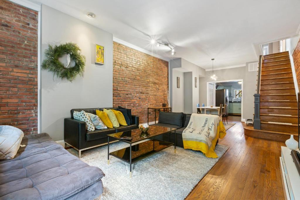 a living room with a couch and a brick wall at Pristine Townhouse With Rooftop Deck Near Canton! in Baltimore