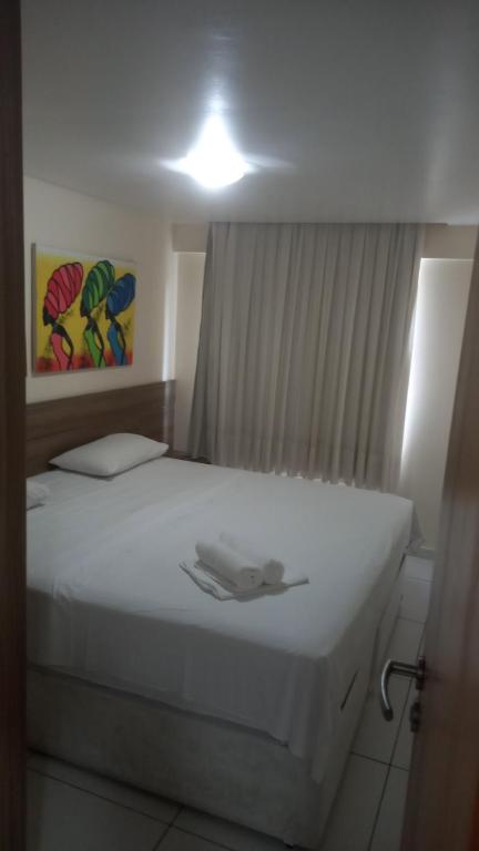 a bedroom with a white bed with a light on it at Israel Flat Tambaú - 213 in João Pessoa