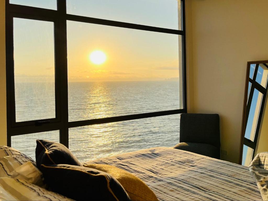 a bedroom with a window with a view of the ocean at Beachfront Luxury Seaside Condo + Pool & Jacuzzi in Rosarito