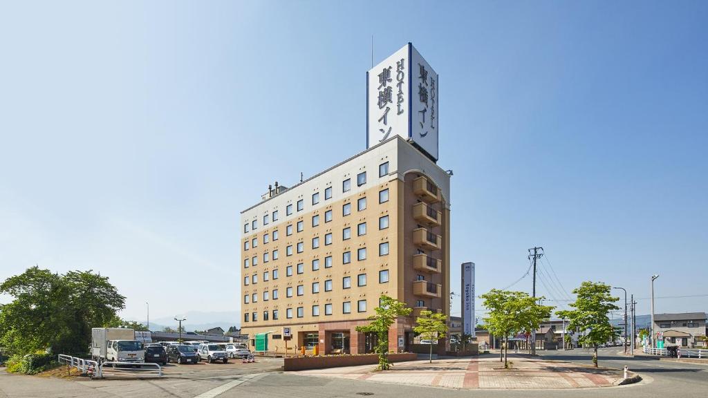 ein hohes Gebäude mit einer Uhr darüber in der Unterkunft Toyoko Inn Yonezawa Ekimae in Yonezawa