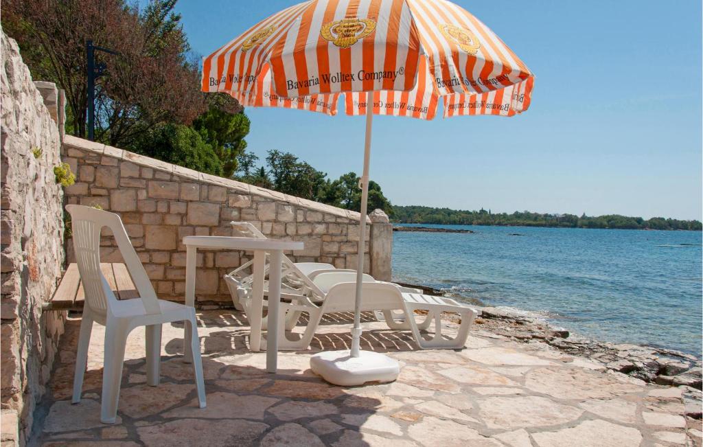 a table and chairs and an umbrella next to the water at 2 Bedroom Nice Home In Sveti Ivan in Sveti Ivan