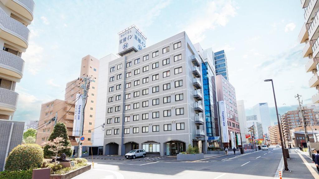 Un bâtiment blanc avec une tour d'horloge en haut dans l'établissement Toyoko Inn Sendai Higashi-guchi No 2, à Sendai