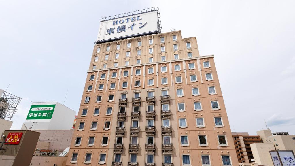 Toyoko Inn Morioka Ekimae في موريوكا: مبنى طويل عليه ساعة