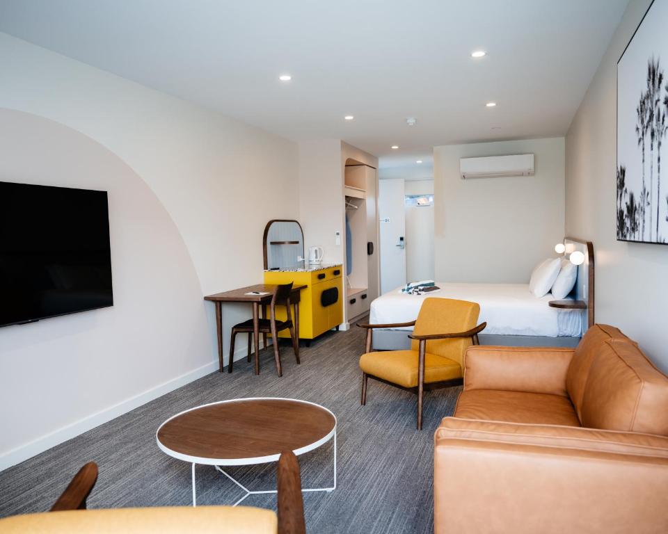 um quarto de hotel com uma cama, um sofá e uma mesa em Peninsula Hotel Motel em Adelaide