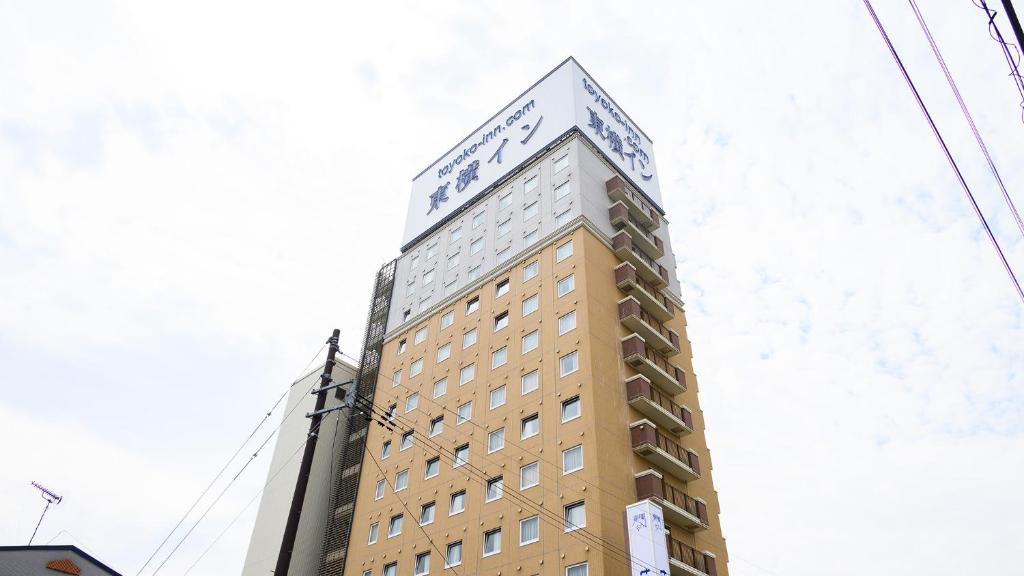 un edificio alto con un cartel encima en Toyoko Inn Shin-shirakawa Ekimae, en Nishigo