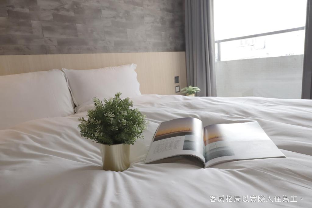 a book and a vase with a plant on a bed at Talmud Hotel Yizhong in Taichung