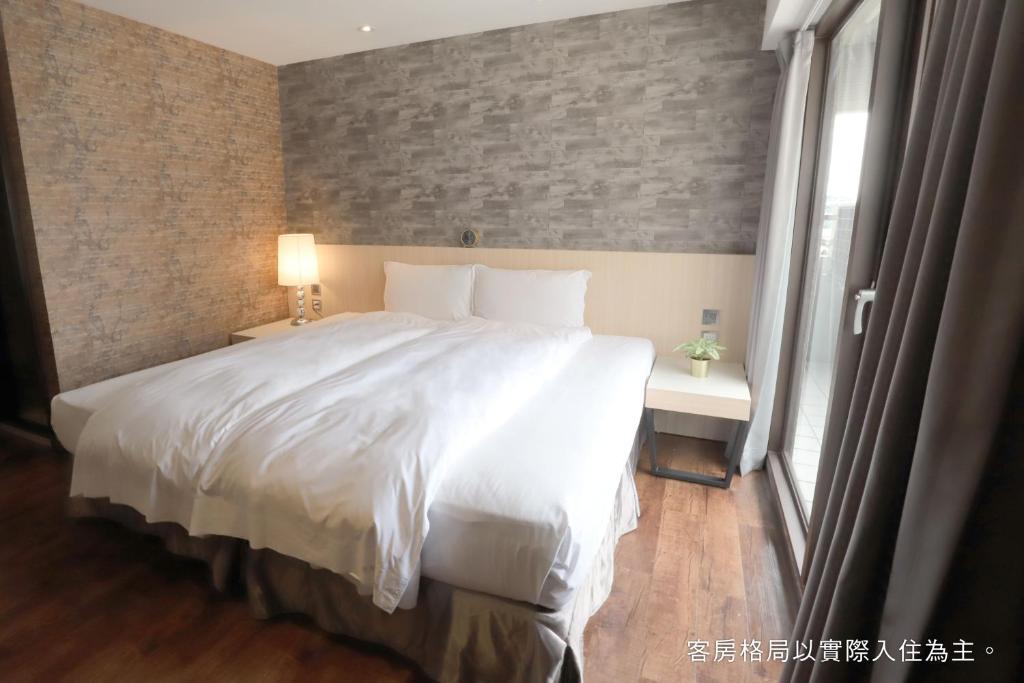 a bedroom with a large white bed and a window at Talmud Hotel Yizhong in Taichung
