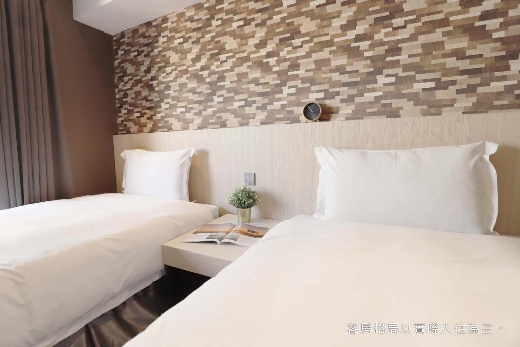 two beds in a hotel room with white sheets at Talmud Hotel Yizhong in Taichung
