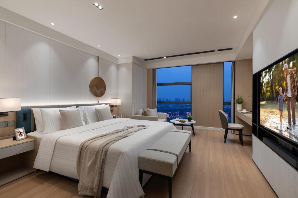 a bedroom with a large bed and a flat screen tv at Somerset Taihu New City CBD Wuxi in Wuxi