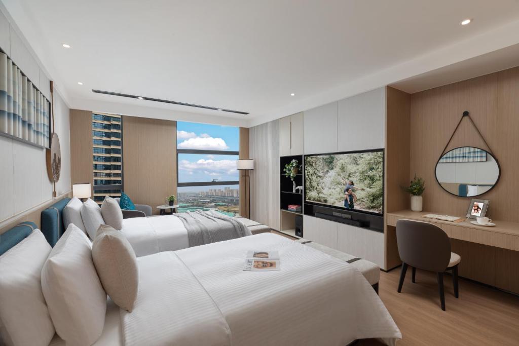 a hotel room with two beds and a flat screen tv at Somerset Taihu New City CBD Wuxi in Wuxi