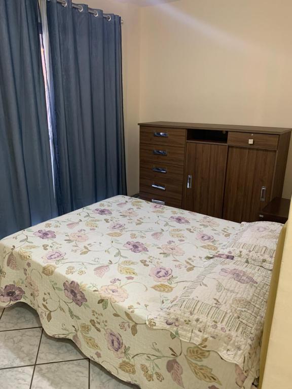 a bedroom with a bed with a flowered blanket on it at Solar de Bruna - Apartamento com 2 Qts - 1 Suíte - Garagem coberta - Wi-Fi - Netflix - Acomoda 6 pessoas a 70 metros da praia in Guarapari