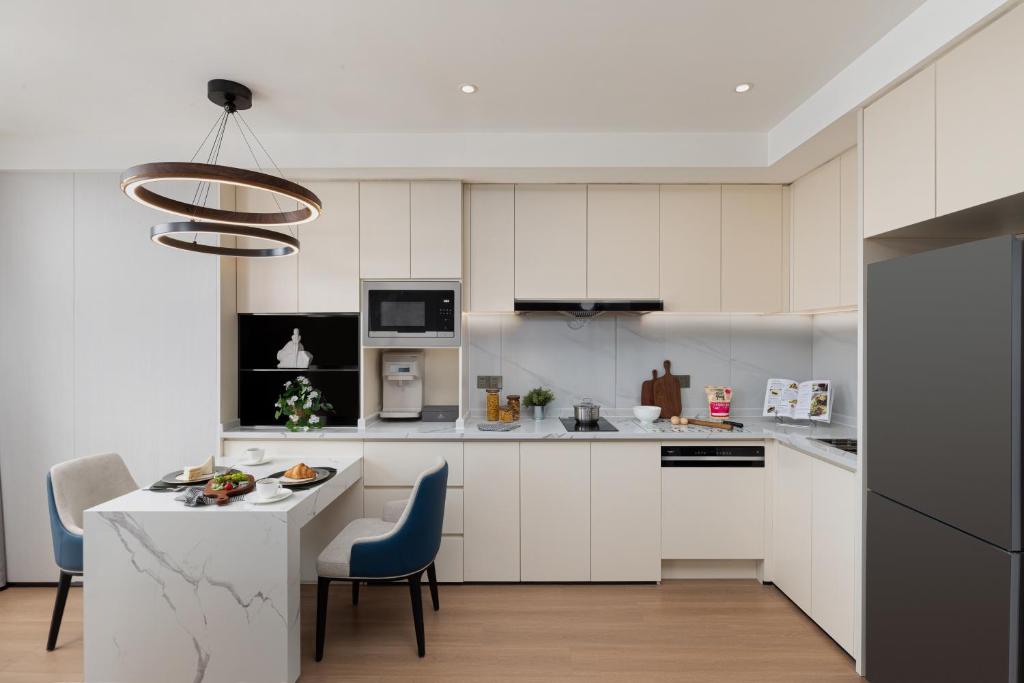 a kitchen with white cabinets and a table and chairs at Somerset Taihu New City CBD Wuxi in Wuxi