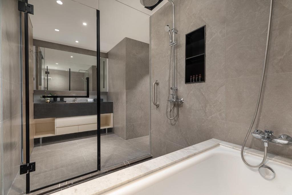 a bathroom with a shower and a bath tub at Somerset Taihu New City CBD Wuxi in Wuxi