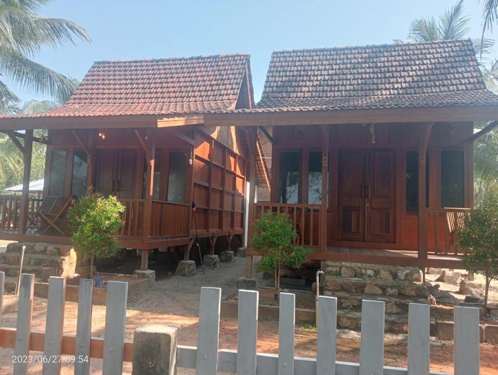 una casa de madera con una valla delante en JN Cottage dan Camping Ground en Karimunjawa