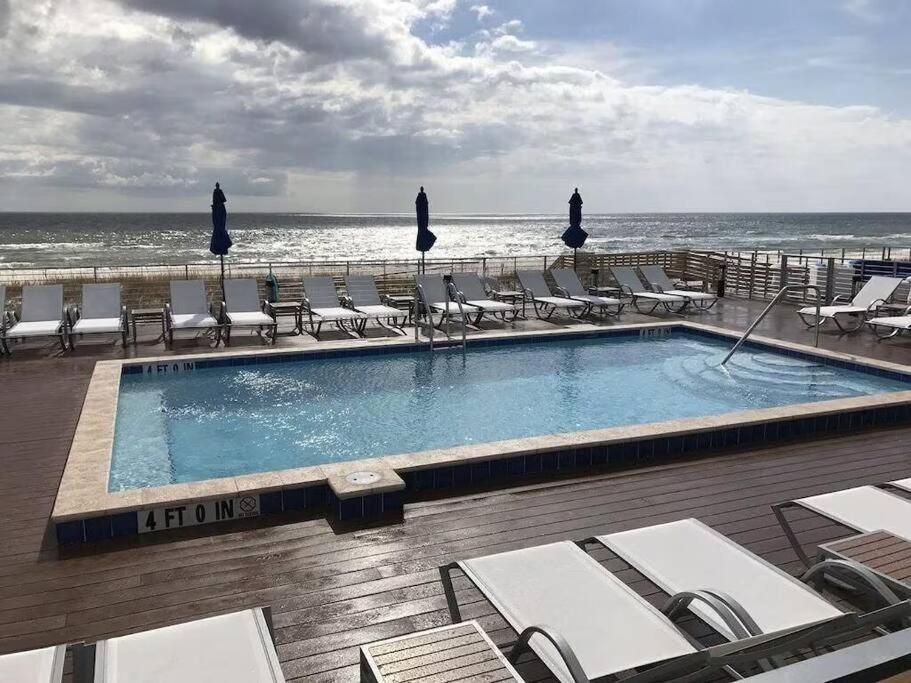 a swimming pool with chairs and the ocean in the background at Foxy Palmer! 3 bedroom 2 bath in Perdido Golf Resort in Pensacola