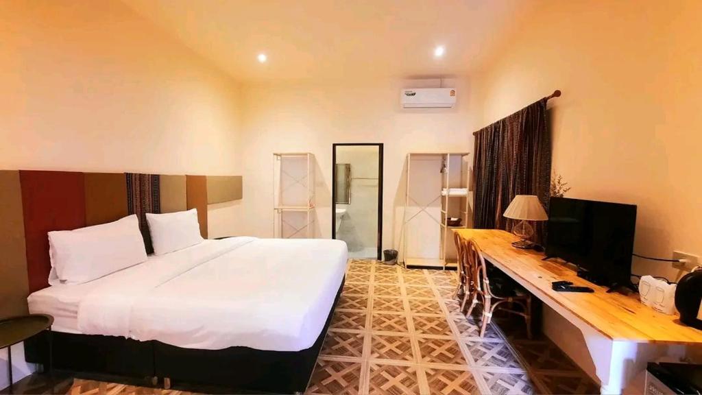 Dormitorio con cama, escritorio y TV en กมุทมาศ สวรรคโลก, en Ban Pa Muang (1)