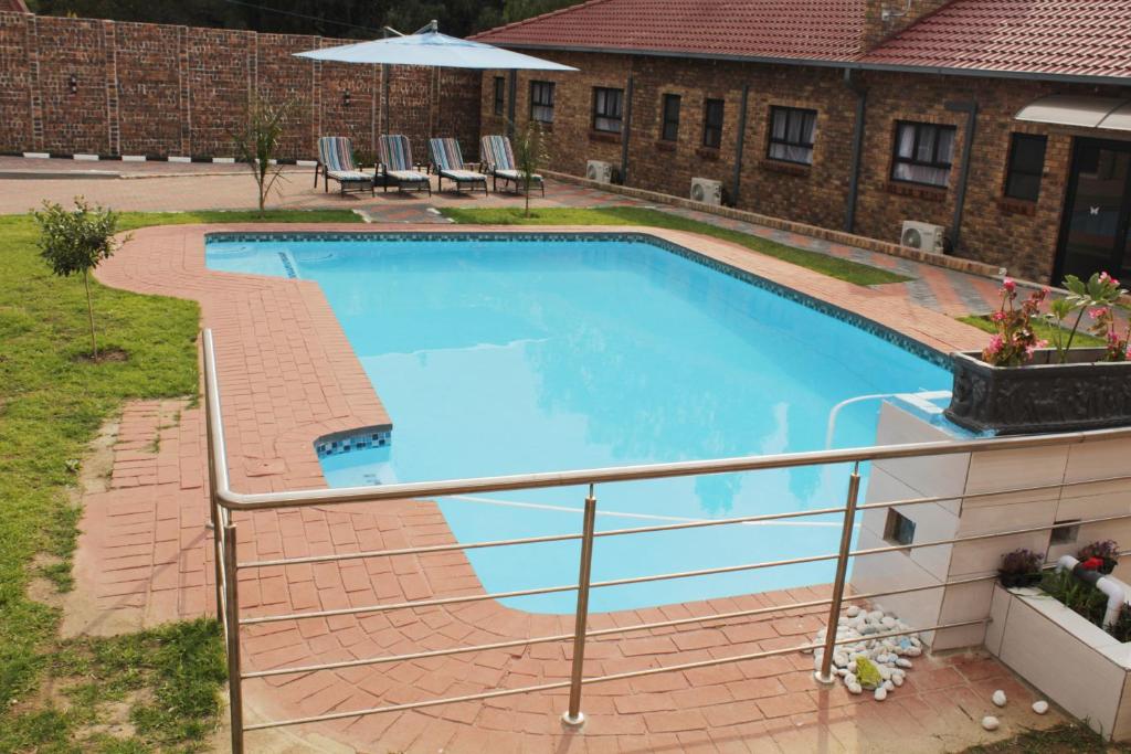 a swimming pool with a rail next to a building at EMPEROR LODGE AND TOURS in Germiston