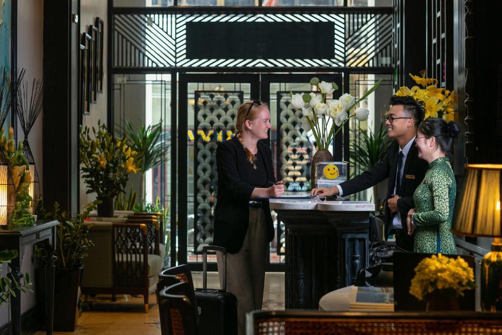 een groep mensen die rond een tafel in een kamer staan bij Scent Premium Hotel in Hanoi