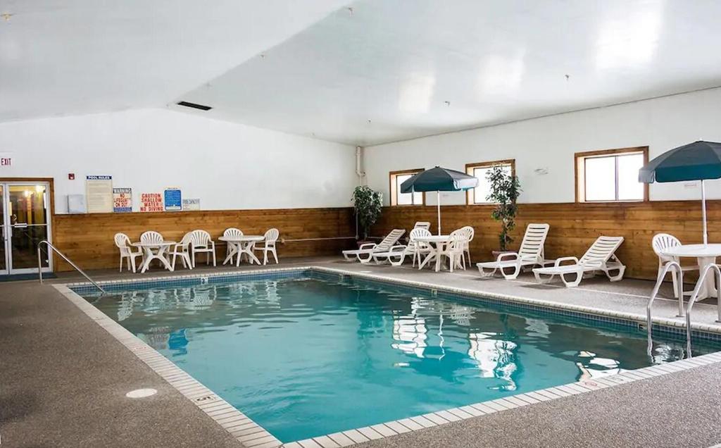 a swimming pool with chairs and tables and umbrellas at Norwood Inn and Suites - Minneapolis-St Paul Roseville in Roseville