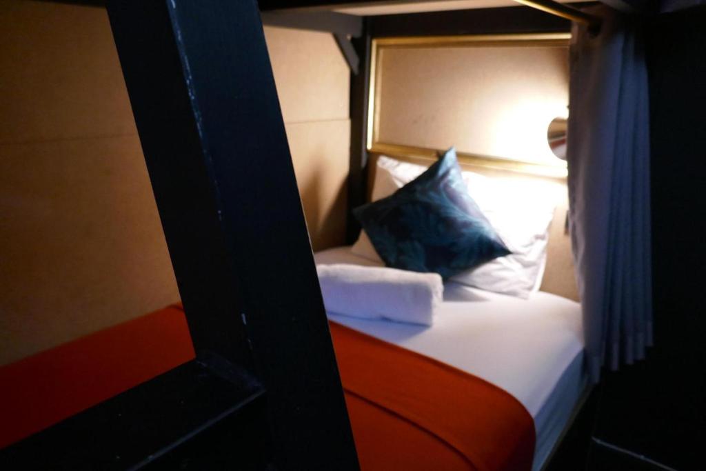una piccola camera da letto con un letto con un cuscino blu di 2street Hostel a Suratthani