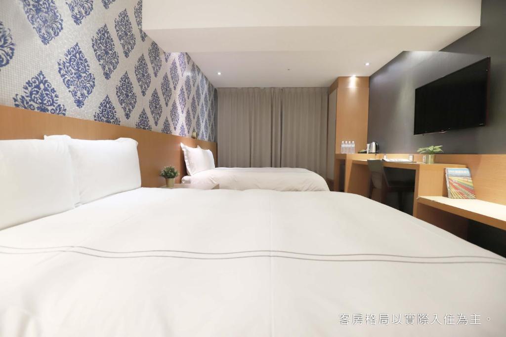 a hotel room with a large white bed and a desk at Talmud Hotel Yizhong in Taichung