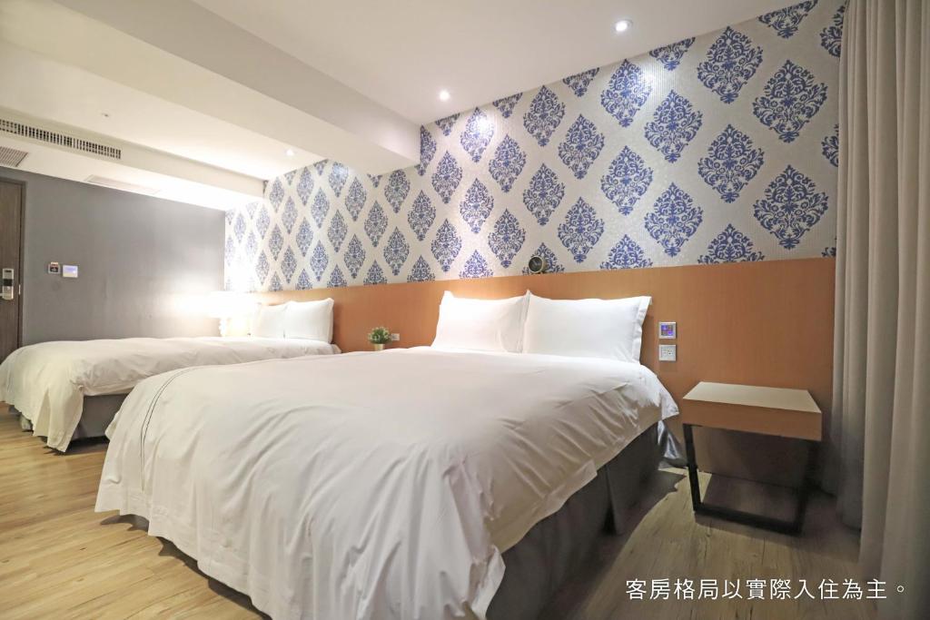 a bedroom with two beds and a blue and white wall at Talmud Hotel Yizhong in Taichung