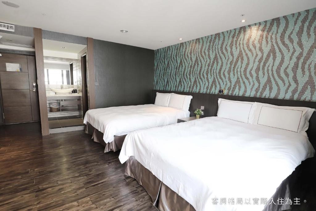 a hotel room with two beds and a bathroom at Talmud Hotel Yizhong in Taichung