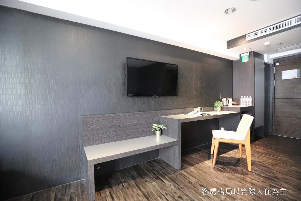 a room with a desk and a tv on a wall at Talmud Hotel Yizhong in Taichung