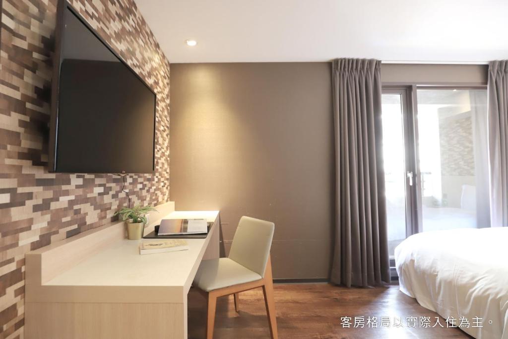 a bedroom with a desk with a bed and a tv at Talmud Hotel Yizhong in Taichung