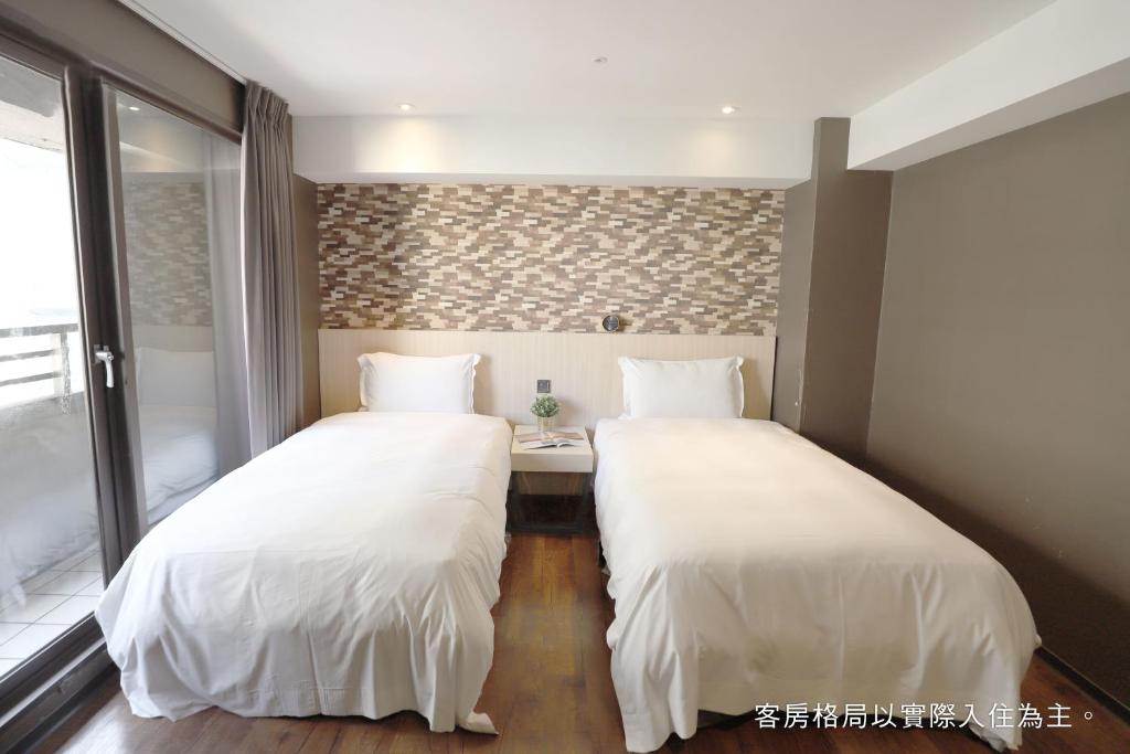 two beds with white sheets in a room at Talmud Hotel Yizhong in Taichung