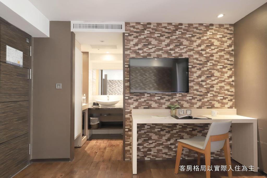 a bathroom with a sink and a television on a wall at Talmud Hotel Yizhong in Taichung