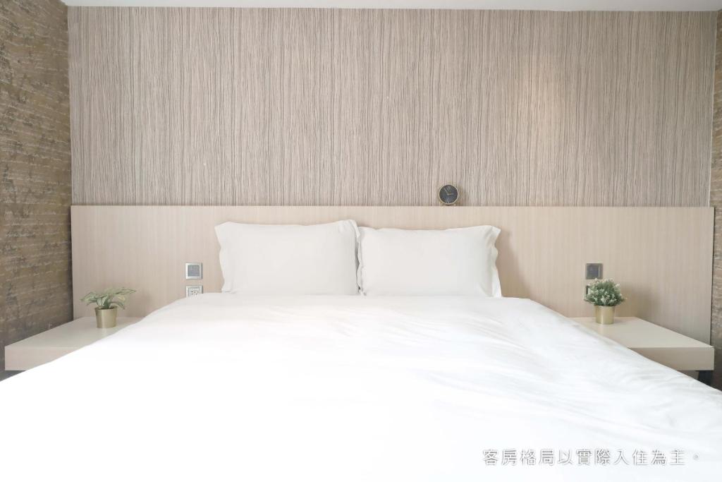 a white bed with white pillows in a bedroom at Talmud Hotel Yizhong in Taichung