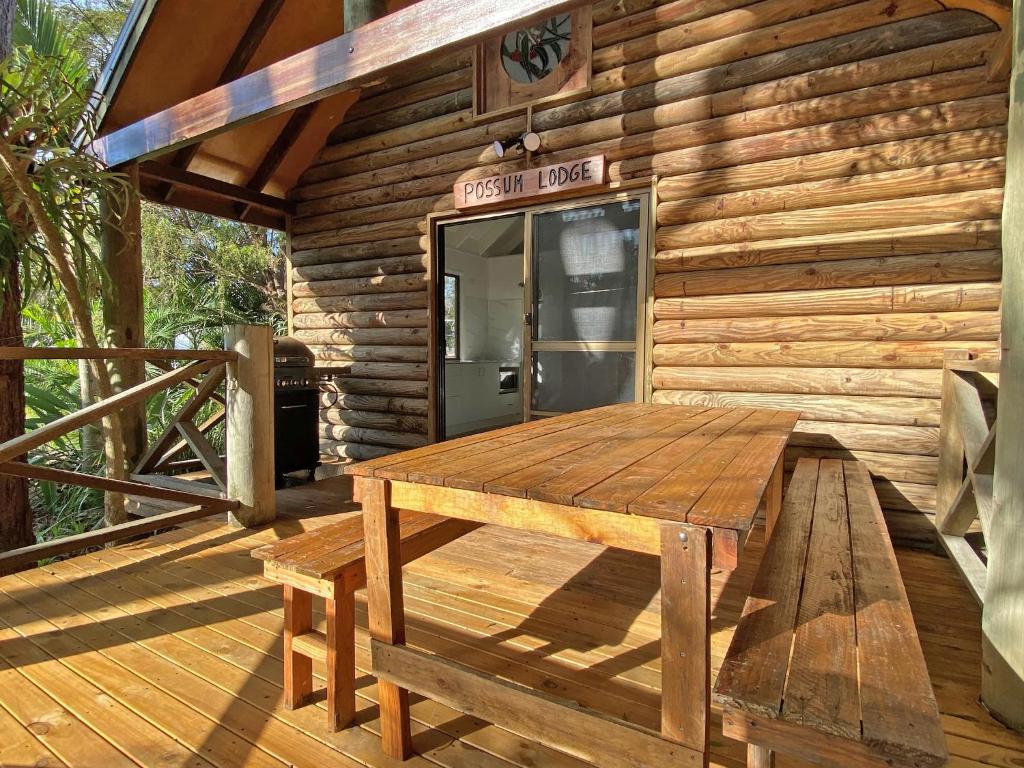 uma cabina de madeira com uma mesa de madeira num deque em BELLES ON BALLOW - POSSUM LODGE em Amity Point