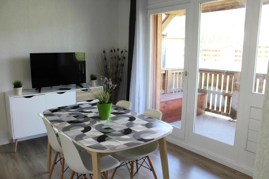 une salle à manger avec une table avec des chaises et une télévision dans l'établissement Résidence Les Chaumettes - TRES BEL APPARTEMENET ENTIEREMENT RENOVE MAE-0124, à Saint-Étienne-en-Dévoluy