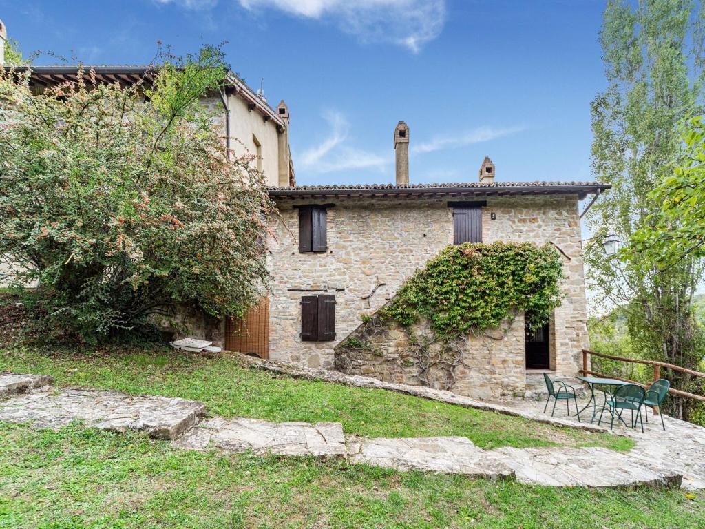 Casa de piedra con 2 sillas y mesa en Captivating Apartment in Assisi with Swimming Pool, en Asís