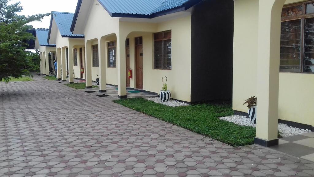 une rangée de maisons avec une passerelle devant dans l'établissement Remarkable 10-Bed Cottages in Bagamoyo, à Bunju