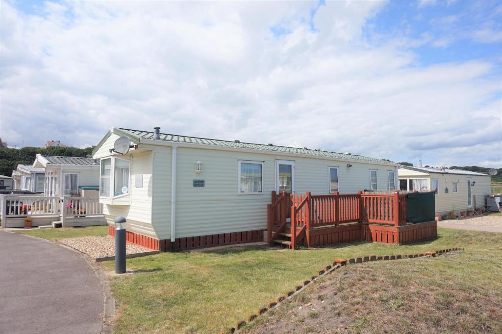 una casa blanca con una valla en un patio en Great 6 Berth Caravan With Decking By The Beach In Suffolk Ref 40023nd en Lowestoft